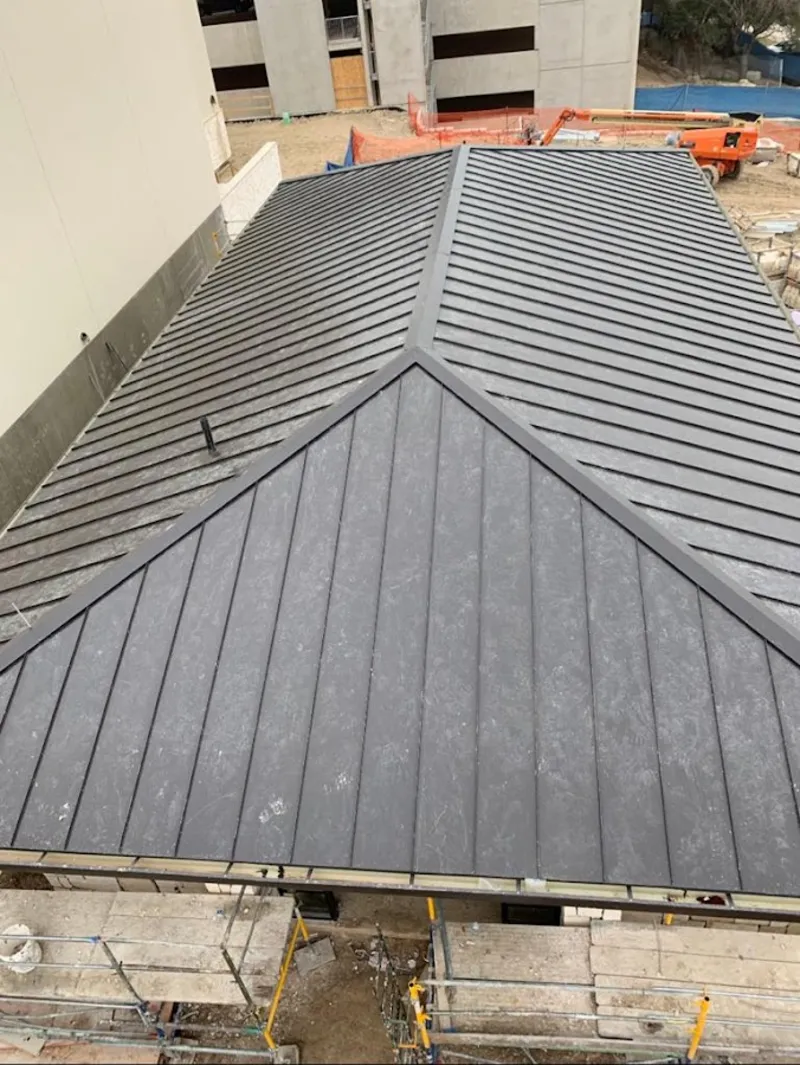 Commercial metal roof construction with crane equipment in Floris